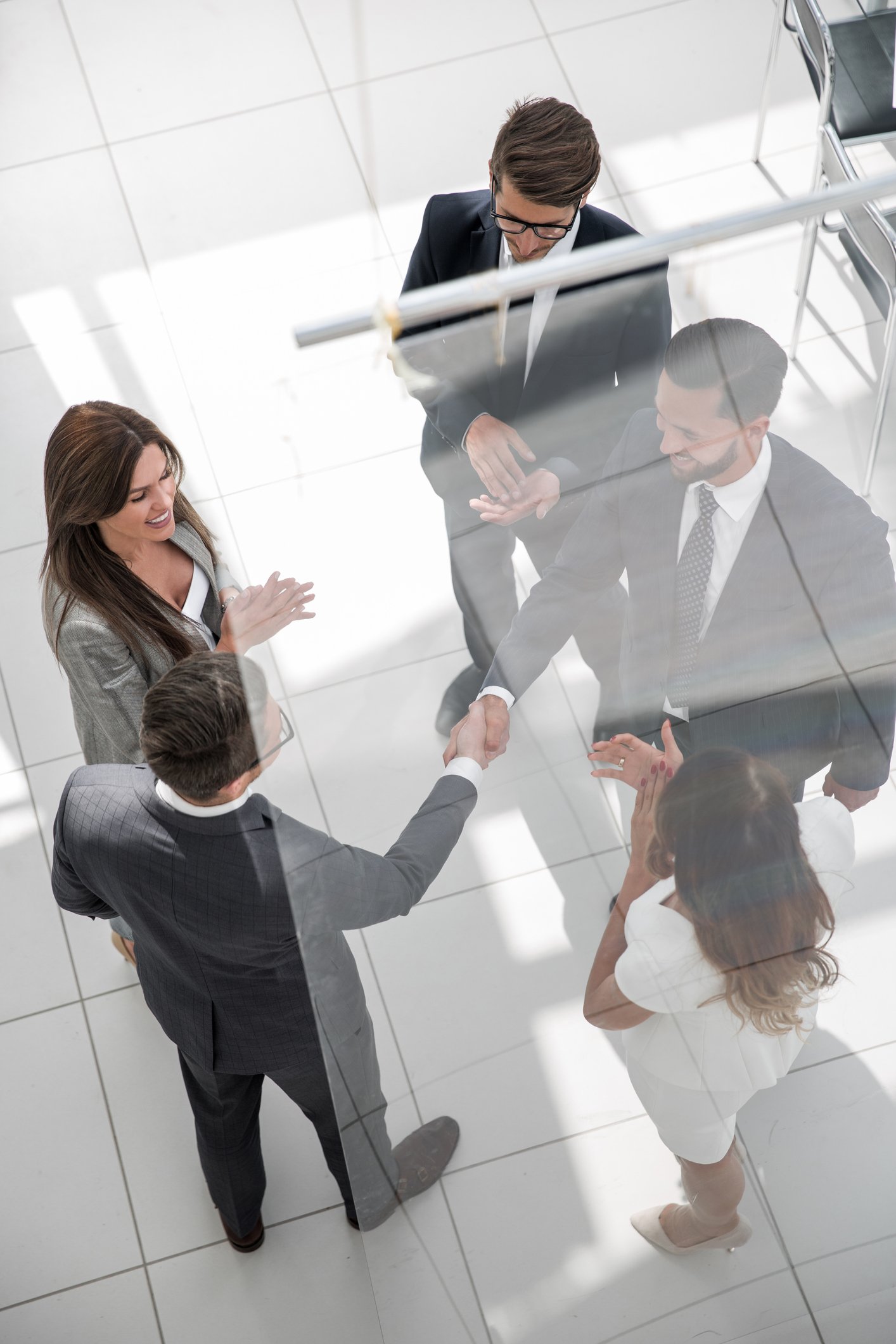 handshake business partners behind the glass door